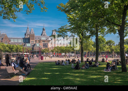 Menschen entspannen an einem warmen sonnigen Tag in der Nähe der Wahrzeichen Rijks Museum, Amsterdam, Niederlande Stockfoto