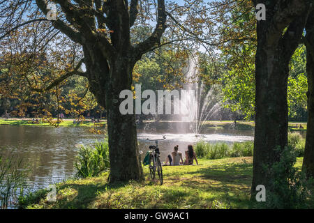 Junge Menschen entspannen in der Nähe von See und Brunnen im beliebten Vondelpark am sonnigen Tag, Amsterdam, Niederlande Stockfoto