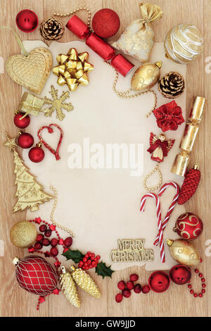 Rot und gold Weihnachten umrandet mit Baumschmuck und Kugeln über helle Eiche Hintergrund auf Pergamentpapier. Stockfoto