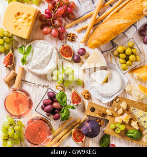 Auswahl an Käse, Obst, Brot, Wein und Snacks auf weiß Stockfoto