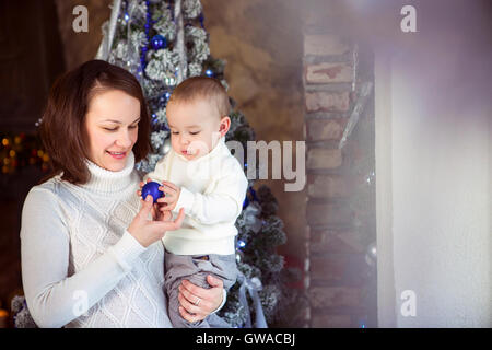 Glückliche Mutter mit ihrem Baby in der Nähe von the Christmas tree Stockfoto