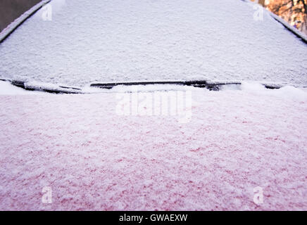 Schnee und Eis bedeckt rotes Auto und Fenster außerhalb im Dezember Closeup. Stockfoto