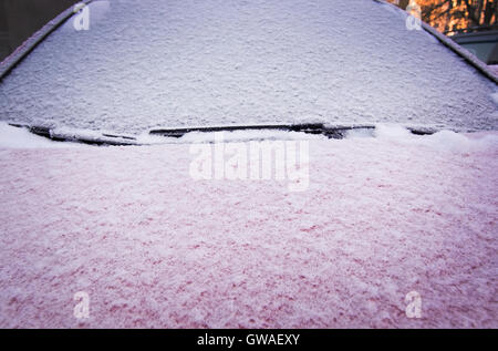 Schnee und Eis bedeckt rotes Auto und Fenster außerhalb im Dezember Closeup. Stockfoto