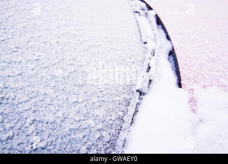 Schnee und Eis bedeckt rotes Auto und Fenster außerhalb im Dezember Closeup. Stockfoto