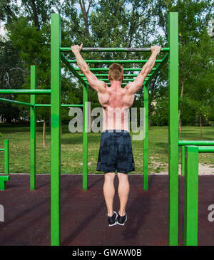 TOUNG Mann tut Pull Ups auf horizontale Leiste im freien Stockfoto