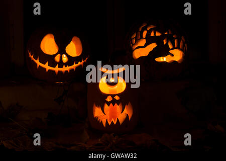 Fotomontage von drei Kürbisse für Halloween. Jack, einem Zyklopen und Hände des Kürbis gegen Herbstlaub und Kerzen Stockfoto