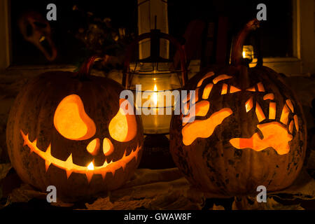 Fotomontage von zwei Kürbisse zu Halloween. Jack und schrecklich Hände gegen eine alte Fenster, trockene Blätter und ein schreckliches Gespenst in
