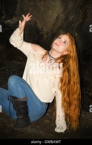 Schöne rote Kopf in skinny-Jeans, weißes Top und schwarze Stiefel, gefährlich sitzt in der Ecke eine kleine Höhle in Connecticut. Stockfoto