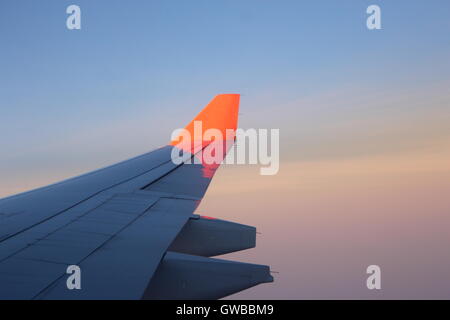 Blick durch Verkehrsflugzeug Fenster hoch über Wolken bei Sonnenuntergang Stockfoto