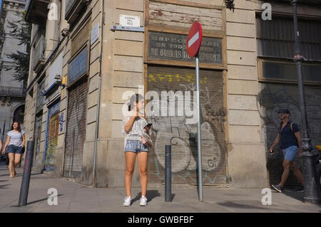 Eine junge Frau stehen auf einer Straße in Barcelona mit ihrem Telefon. Stockfoto