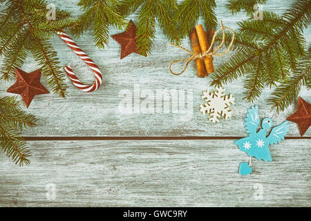 Retro stilisierte Weihnachten Hintergrund, Fichte Zweige mit Verzierungen auf einem rustikalen Holztisch, Ansicht von oben mit Textfreiraum. Stockfoto