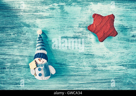 Vintage stilisierte Schneemann Spielzeug und roten Stern auf einem blauen rustikalen Holztisch, Draufsicht, Weihnachten Hintergrund mit Textfreiraum. Stockfoto