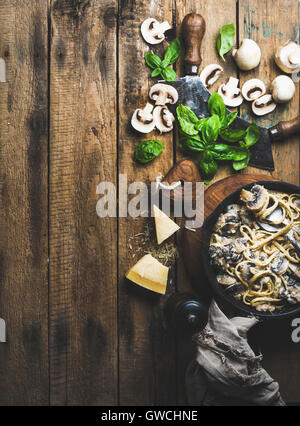 Abendessen im italienischen Stil. Hausgemachte cremige Pilz Pasta Spaghetti in Gusseisen Pfanne mit Parmesan-Käse, frische Basilikumblätter und pep Stockfoto