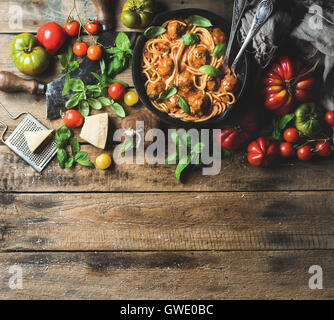 Italienische Pasta Spaghetti mit Tomatensauce und Fleischbällchen in gusseisernen Pfanne serviert mit Parmesan-Käse, frischem Basilikum und bunte t Stockfoto