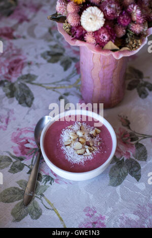 Himbeer Smoothie Schüssel garniert mit Kokos und gehackte Paranüsse auf dem Tisch Stockfoto