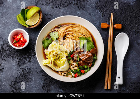 Würzige asiatische Nudeln in Brühe mit Rindfleisch auf dunklem Hintergrund Stockfoto