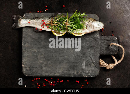 Rohe Forelle mit Zitrone, Kräutern und Gewürzen auf rustikalen Hintergrund Stockfoto