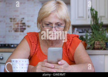Ältere Frau sendet Sms auf Handy Stockfoto