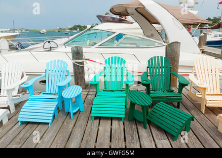 Bunte Kunststoff Sessel auf dem Steg in der Marina mit Motorboot im Hintergrund. Stockfoto