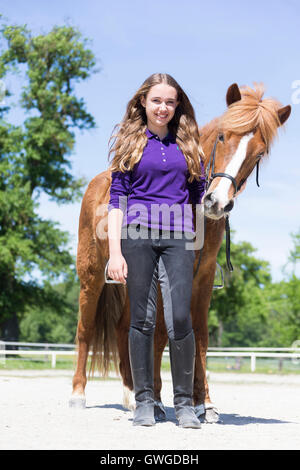 Islandpferd. Mädchen stehen neben ein rotes Pferd mit Tack auf einem Reitplatz. Österreich Stockfoto