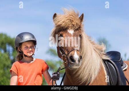 Islandpferd. Mädchen stehen neben ein rotes Pferd mit Trense. Österreich Stockfoto