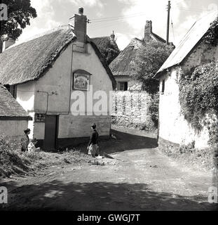 1950er Jahre, Menschen auf einer ländlichen Landspur außerhalb eines alten Reetdachkneibs, The Shipwrights Arms, Helford, Helston, Cornwall, England, Großbritannien. Das Schild links von der Tür steht für 'Devenish's Pale Ale'. Stockfoto