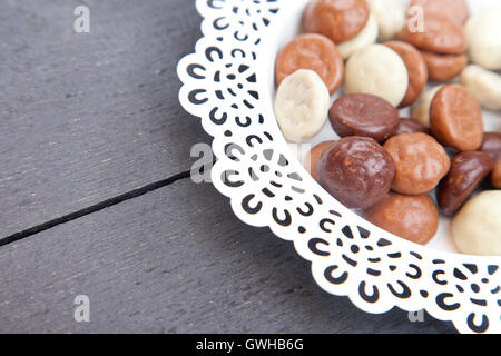 Niederländischen Süßigkeiten Schokolade Pepernoten auf weißen Teller auf schwarzem Hintergrund aus Holz Stockfoto