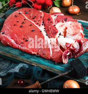 Frisches Rindfleisch Kalbfleisch auf rustikalen Holztisch mit Küchenutensilien und Gemüse, quadratische Komposition Stockfoto