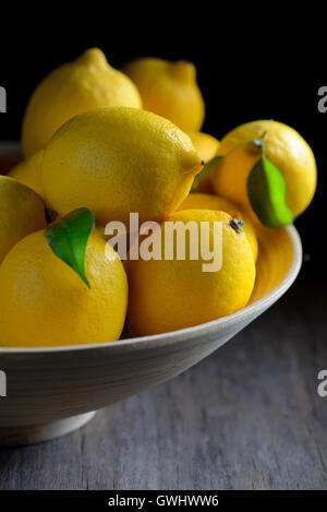 Frische Zitronen mit Blättern in Platte Stockfoto