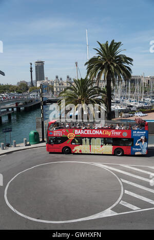 Barcelona Touristenbus am Wendepunkt durch das Einkaufszentrum Maremagnum mit einem Blick der Port Vell und Palmen hinter. Stockfoto