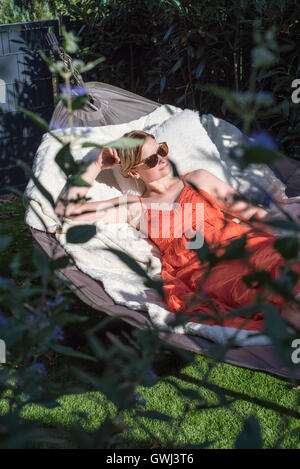 schöne blonde Frau ist entspannend in einer Hängematte in der Sonne Stockfoto