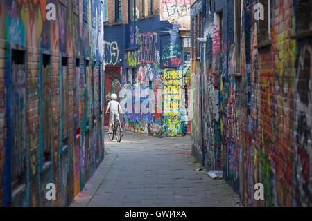 Kind auf Fahrrad zwischen Wänden voller Grafiti in der belgischen Stadt Ghent Stockfoto
