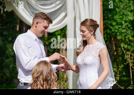 Bräutigam trägt den Ring an der Hand der Braut bei einer Trauung Stockfoto