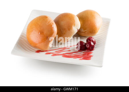 Pastetchen mit Kirschen auf weißem Teller auf dem weißen Hintergrund isoliert. Stockfoto