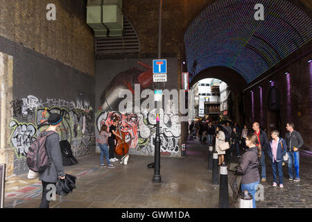 Ein paar Musiker als Straßenmusikant auf Clink Street, London, von einer Schar von Passanten beobachtet Stockfoto