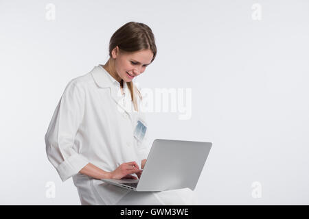 Lächelnd Ärztin arbeitet auf ihrem Laptop vor einem weißen Hintergrund Stockfoto