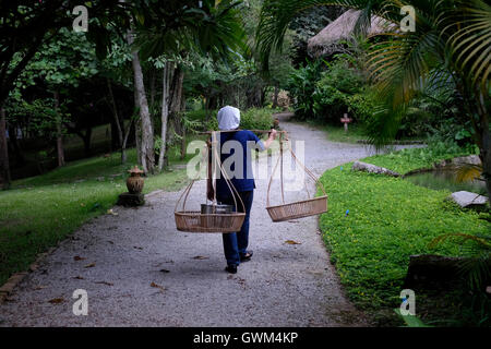 Ein Arbeiter tragen Kochtopf in Hmong Hilltribe Lodge liegt im Amphoe Mae Rim, Chiang Mai, Nordthailand Stockfoto