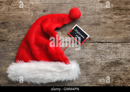 Santa Pelzmütze mit einem kleinen Panel Frohe Feiertage in französischer Sprache geschrieben Stockfoto