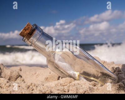 Flasche mit Nachricht stecken in den Sand am Strand Stockfoto