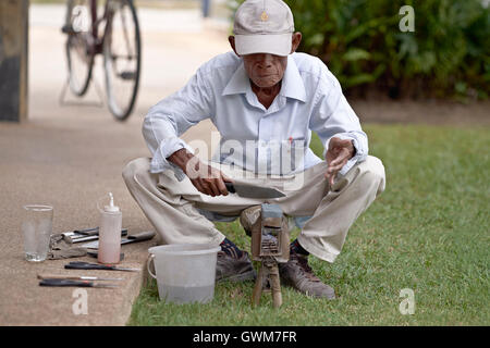 Messerschleifer. 75-jähriger älterer Mann bei der Arbeit, der Haushaltsgeräte schärft. Thailand S. E. Asien Stockfoto