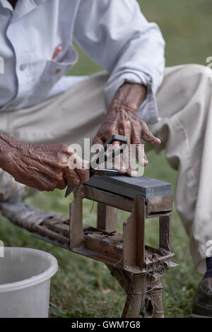 Messerschleifer schärft eine Schere. Hände eines älteren asiatischen Mannes bei der Arbeit. Thailand Südostasien Stockfoto