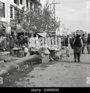 1950er-Jahren, zeigt historische Bild einer Straße in Kabul, Afghanistan, afghanische Markthändler auf dem Bürgersteig. Stockfoto