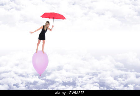 Barfuß Mädchen über einen Ballon, hält sie im Gleichgewicht mit einem roten Regenschirm während des Fluges über weiße Wolken am blauen Himmel Stockfoto