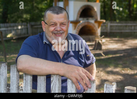 Outdoor Portrait von älteren ukrainischen Bauern stehen in der Nähe von Holzzaun mit glücklichen Lächeln Stockfoto