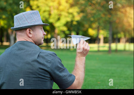 Mann mit einem Papierflieger in der Hand auf Wiese Stockfoto