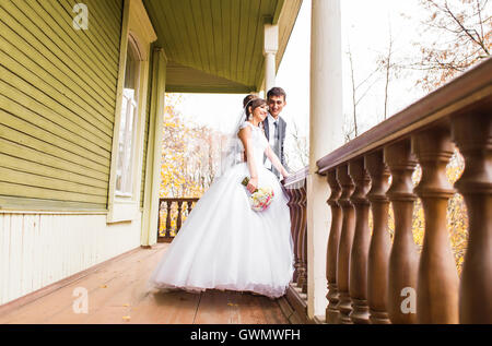 Braut und Bräutigam stehen in der Nähe ein Haus aus Holz. Hochzeit im rustikalen Stil. Stockfoto