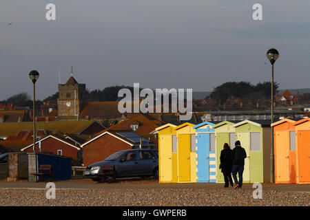 Menschen zu Fuß vorbei an Linie der hölzernen Umkleidekabinen am Meer auf eine Winter-Nachmittag, Seaford, East Sussex, England Stockfoto