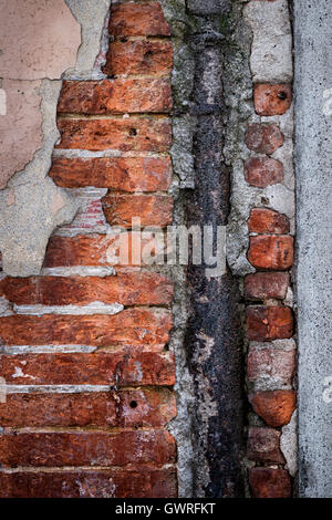 Antike Wand mit roten alten Ziegeln, rostigen Metall und Schichten von Gips in Toulouse, Frankreich, Nahaufnahme. Stockfoto