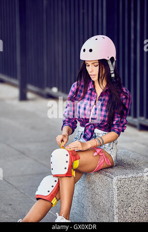 Schönes Mädchen setzt auf Schutzbekleidung für Inline-Skating Stockfoto