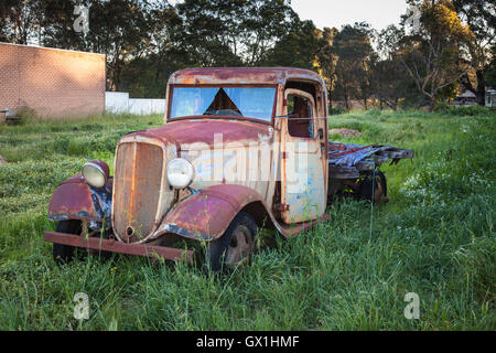 Eine rostige alte LKW, hohen Gras neben einem gebrauchten Auto Hof Stockfoto